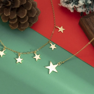 Minimalistische gouden ketting met stervormige hangers tegen een kerstachtergrond