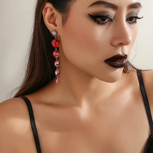 Detail of long marble texture drop earrings on model in warm lighting