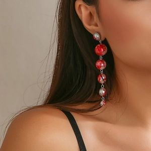 Detailed macro view of long drop earrings with red and silver marbled beaded texture