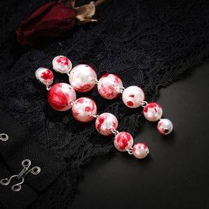 Gothic pearl earrings with red blood drop effect and black lace background macro detail