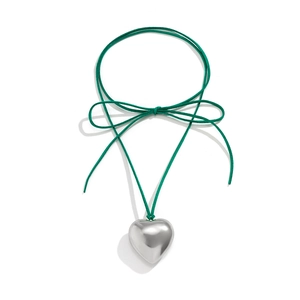 Detail of a polished silver heart pendant with a deep green velvet cord and bow tie
