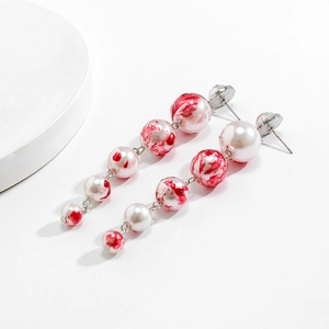 Close-up of gothic beaded tassel earrings with red marble texture and gradient pearls