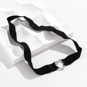 Gros plan d'un choker élastique noir avec boucle cœur argentée sur support en pierre