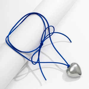 Close-up of a 3D heart pendant with polished silver finish on a blue cord necklace
