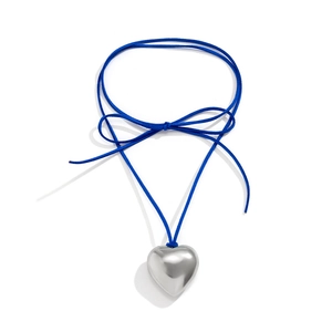 Detail view of a large silver heart pendant with a blue adjustable cord and bow knot