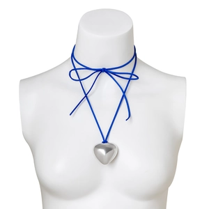 Detail of silver heart pendant with royal blue velvet cord tied as a bow on a mannequin