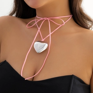 Close-up of a pink suede choker with a large polished silver heart pendant