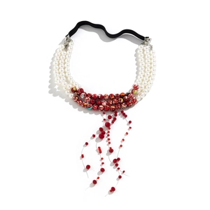 Macro detail of Gothic pearl choker with red bead tassels and elastic black band