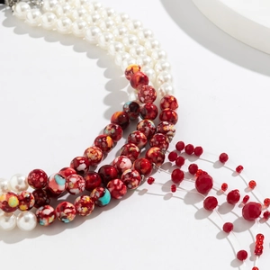 Detail of layered gothic necklace featuring white pearls and red blood-drop crystal tassels