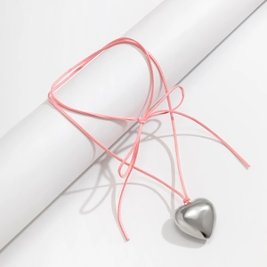 Macro shot of large silver heart pendant on pink adjustable cord necklace with bow detail