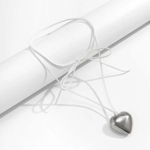 Close-up of a white adjustable cord necklace with a polished silver heart pendant