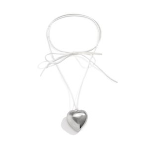 Close-up of large polished silver heart pendant on white adjustable cord with bow