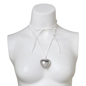 Detail of a large silver heart pendant on a white velvet cord choker necklace