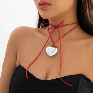 Detail of red choker necklace featuring a large mirror-polished silver heart pendant