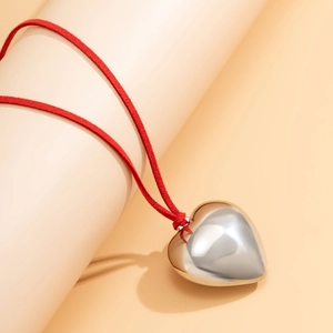 Detailed view of a polished silver heart pendant on a premium red velvet cord choker