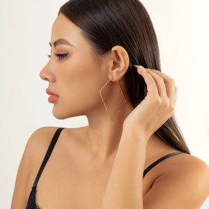Close-up of model wearing large golden geometric diamond earrings with matte texture