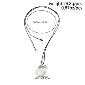 Detail view of a large clear heart pendant on a long adjustable black wax cord necklace