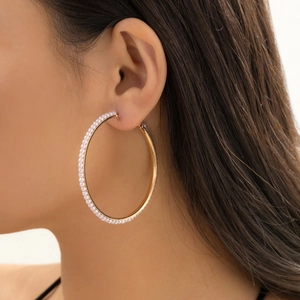 Detailed view of large gold hoop earring with pavé-set pearls on model ear