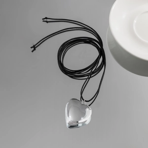 Macro shot of transparent heart pendant with adjustable black wax cord choker necklace