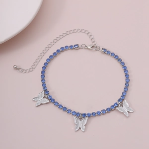 Detail of silver chain anklet with blue rhinestones and crystal butterfly charms