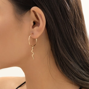 Close-up of a gold hoop earring with a snake pendant on a model's ear in side profile
