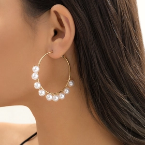 Macro detail of gold hoop earrings with wrapped pearls on female model ear