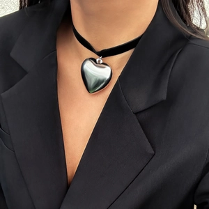 Close-up of polished silver heart pendant on a wide black velvet choker necklace