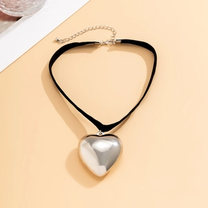 Detail view of large polished silver heart pendant on a black velvet choker necklace