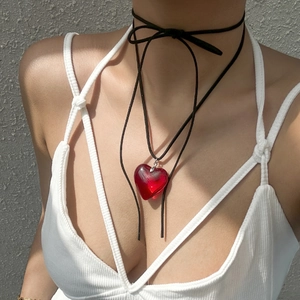 Detail of adjustable black cord choker with a vibrant red heart-shaped pendant on model