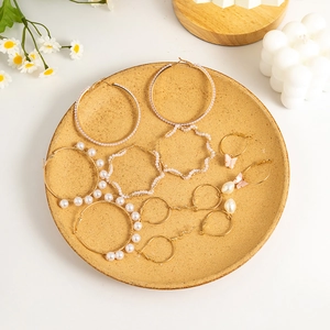 Set of gold earrings with pearls, pink butterfly charms, and stars on a white tray