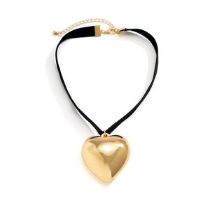 Detail of black ribbon choker featuring a large polished gold heart pendant with adjustable chain