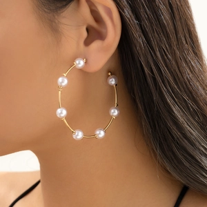 Close-up of elegant gold hoop earrings with white pearls on female model