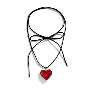 Detail of red heart pendant with elegant black ribbon bow on minimalist cord