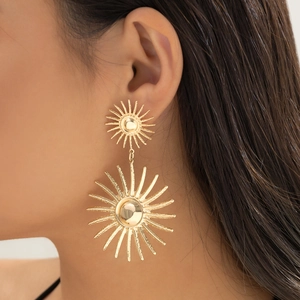 Close-up of golden sunburst statement earrings with radiant layered circular patterns