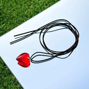 Close-up of a vibrant red 3D heart pendant on a black adjustable wax cord necklace