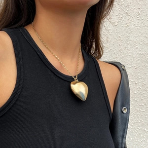 Detail shot of a 3D heart pendant necklace with high-polished gold finish on model