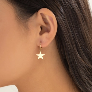 Close-up of elegant gold star pendant earring worn by model in a soft lighting profile view