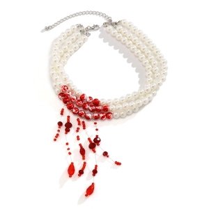 Detailed view of layered white faux pearl necklace with red crystal blood drip tassels