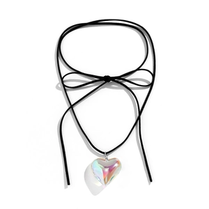 Detail view of a glossy heart-shaped pendant with an adjustable black suede bow necklace
