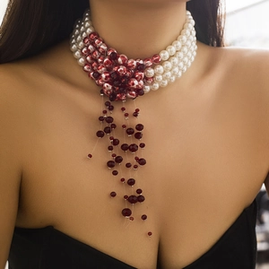 Macro detail of gothic choker featuring layered pearls, red beads, and fringe tassels