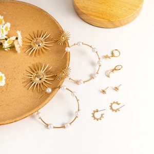 Detailed view of gold pearl earrings and star charm jewelry set on ceramic display