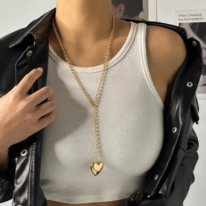 Detailed view of a gold heart pendant necklace on a model wearing a black leather jacket