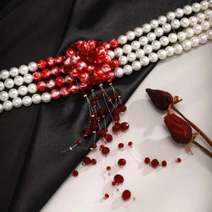 Detail shot of gothic choker with three-row white pearls and red bead tassel fringes