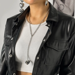 Detail of silver heart pendant necklace and earrings set worn on a fashion model