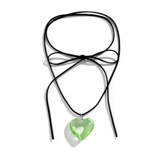Detail of a wax cord choker with a black bow and a green fluorescent heart pendant