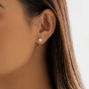 Close-up of elegant silver stud earring with clear round zircon on female model