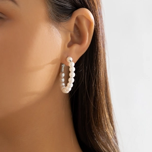 Close-up of a woman wearing French style vintage pearl hoop earrings in silver finish