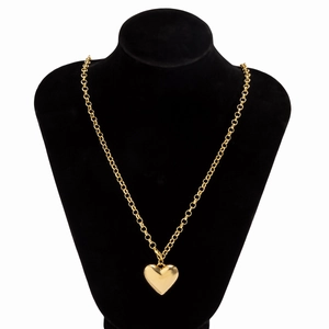 Macro detail of a large polished gold heart pendant on a curb chain necklace