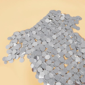Dettaglio macro di paillettes argentate con trama metallica e riflessi lucidi dell'anello