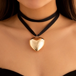 Close-up of a velvet choker necklace featuring a large polished gold heart pendant